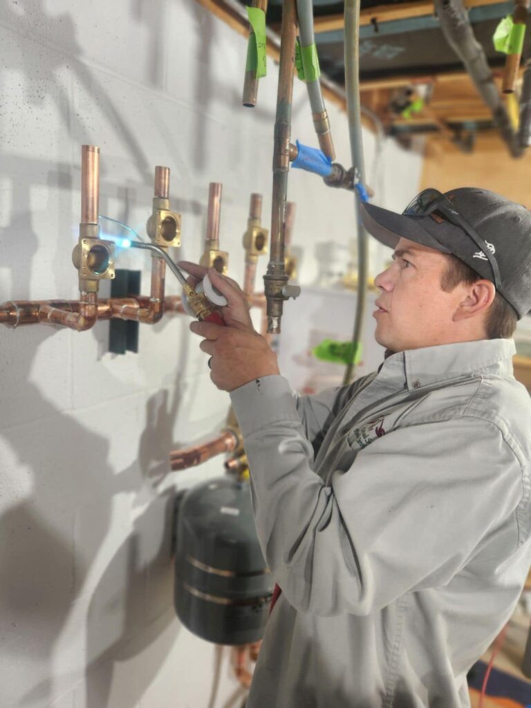 Master plumber Kris Curtis welding copper piping with torch