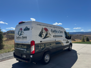 Curtis and Sons Plumbing and HVAC service work vehicles parked outside of a house call in Parker, CO